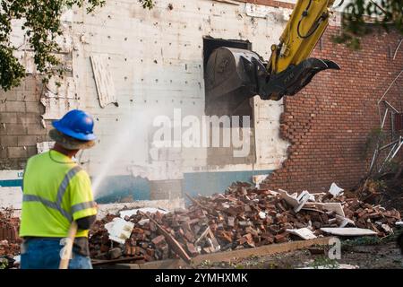 Démolition en cours : les travailleurs gèrent en toute sécurité l'enlèvement d'une structure en brique et en béton avec de la machinerie lourde et la suppression de l'eau Banque D'Images