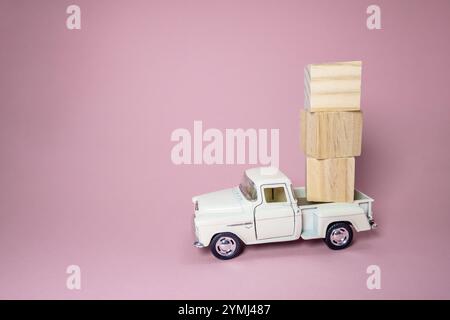 Le camion de jouet blanc transporte des blocs de bois. Le camion est petit et les blocs sont grands. L'image a une ambiance ludique et fantaisiste Banque D'Images