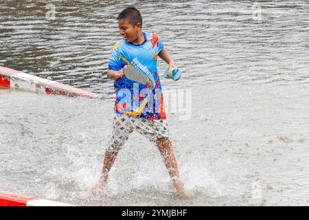 SAMUT PRAKAN, THAÏLANDE, SEP 25 2024, garçon pieds nus courant dans une flaque d'eau dans la rue Banque D'Images