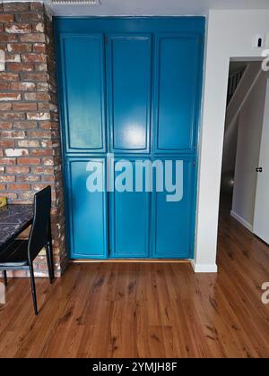 'Intérieur moderne avec une armoire turquoise vibrante, des accents de mur de briques et du parquet. Parfait pour les thèmes du design d'intérieur et de la décoration intérieure. Banque D'Images