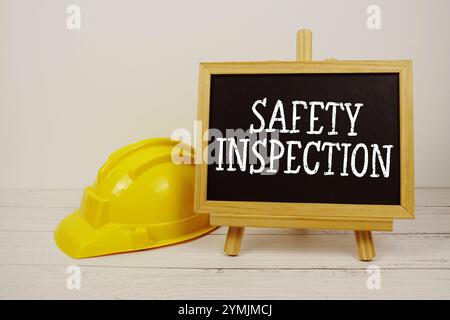 Texte d'inspection de sécurité sur tableau noir avec casque de sécurité sur fond en bois Banque D'Images
