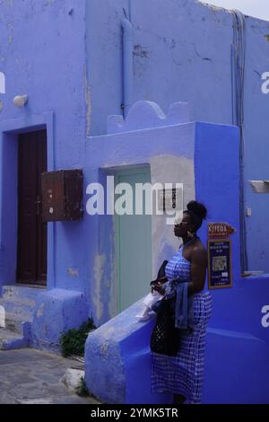 Femme en bleu devant un bâtiment bleu à Oia, Santorin Banque D'Images