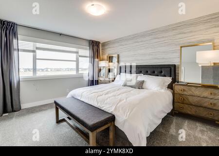 Une chambre avec un grand lit, une commode et un miroir. Le lit est recouvert de draps et oreillers blancs Banque D'Images