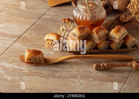 Baklava avec noix et miel sur fond beige. Désert oriental traditionnel dans un plat en bois. Banque D'Images