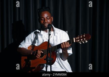 Jouer à la guitare acoustique sur scène avec microphone Banque D'Images