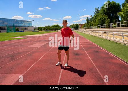 Un homme se tient debout sur une piste portant une chemise rouge et un short Banque D'Images