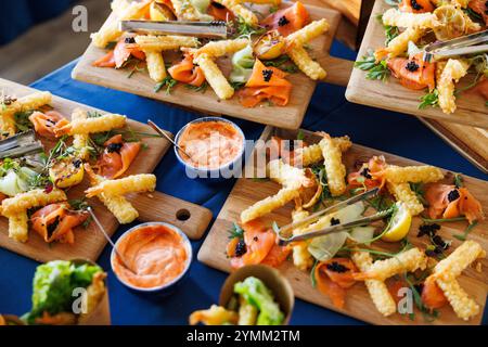 Une table avec une variété de nourriture sur des planches en bois. La nourriture comprend des sandwichs, des frites et d'autres collations. La table est mise en place pour une fête ou un rassemblement Banque D'Images