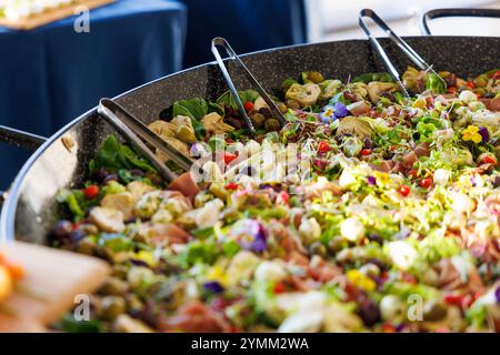 Un grand bol de nourriture avec de nombreux types de légumes et de viande. Le bol est rempli d'une variété de verts et de rouges, et il ressemble à un buffe Banque D'Images