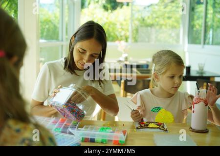 Professeur dans l'atelier a techno deux filles comment assembler une mosaïque thermo Banque D'Images