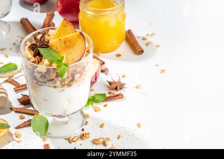 Gâteau au fromage Apple Pie Granola, petit-déjeuner en-cas, dessert avec granola d'avoine, yaourt au fromage à la crème, miel, tranches de pomme et épices à la cannelle sur blanc Banque D'Images