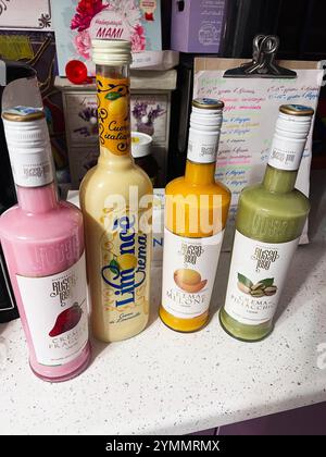 Kiev, Ukraine - 22 novembre 2024 : Collection de quatre liqueurs de crème italiennes exposées sur un comptoir de cuisine, offrant des saveurs comme le citron, la fraise, Banque D'Images