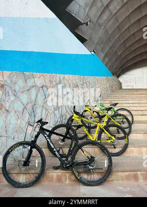 Kiev, Ukraine - 22 novembre 2024 : quatre vélos de montagne Kinetic vibrant, y compris des modèles noirs, jaunes et verts, sont garés sur des marches de pierre sous A. Banque D'Images