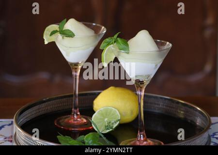 deux verres à cocktail de sorbet au citron aromatisé au basilic et au citron vert sur plateau noir Banque D'Images