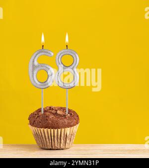 Cupcake au chocolat avec numéro 68 bougie - anniversaire sur fond jaune. Banque D'Images