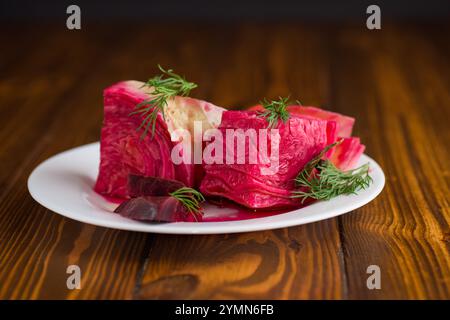 chou mariné avec betteraves et carottes, dans une assiette, sur une table en bois . Banque D'Images