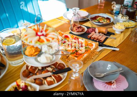 Brunch dynamique avec une variété de plats colorés, salades fraîches, fromages, viandes et boissons. L'arrangement animé crée un chaleureux et dedans Banque D'Images