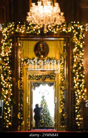 Chef de la fête, Val Goldman, met la touche finale aux arbres de Noël dans le Boudoir bleu du château de Warwick. Une équipe de 35 experts en histoire, costumes et paysages passe 750 heures à planifier et quatre semaines à installer des lumières, des décorations et des arbres avant la saison des fêtes. Il faut 100 heures pour décorer l'intérieur du château, et encore 40 heures dans le parc pour accrocher environ 50 000 lumières de Noël, décorer 30 arbres de Noël autour et poser la traînée lumineuse de 1 680 mètres. Date de la photo : vendredi 22 novembre 2024. Banque D'Images