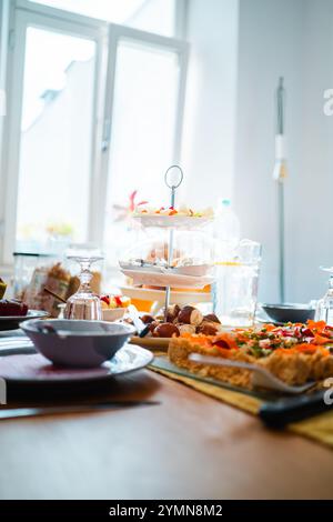 Une salle ensoleillée avec une table de brunch magnifiquement agencée. Il propose une variété de pâtisseries fraîches, fruits et amuse-gueules, parfaits pour un rassemblement chaleureux Banque D'Images