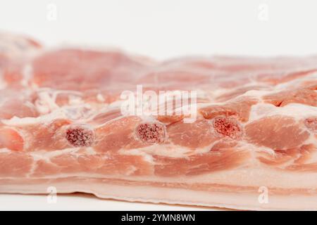 Gros plan d'un morceau de viande avec une tache rouge dessus. La viande est crue et a une couleur rosâtre viande de porc isolée sur un fond blanc. Banque D'Images