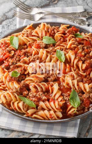 Pâtes bolognaises Fusilloni avec une sauce tomate à la viande copieuse en gros plan sur l'assiette sur la table. Vertical Banque D'Images