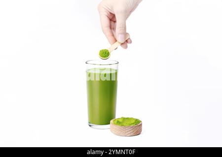 Femme tenant une cuillère en bois avec de la poudre d'herbe de blé, superaliment détox, boisson énergétique, isolé sur fond blanc Banque D'Images