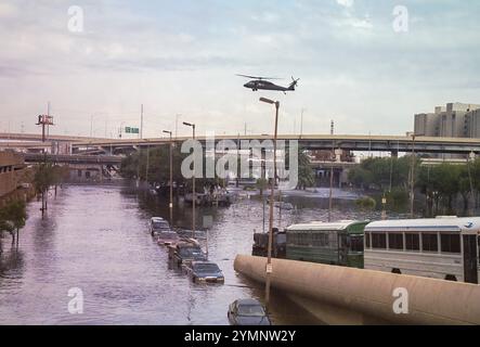 Nouvelle-Orléans, LOUISIANE, États-Unis - 30 août 2005 : un hélicoptère de la Garde nationale secourant les victimes des inondations arrive pour un atterrissage au Superdome au-dessus des rues inondées avec des wagons d'inondation stationnés et des bus d'évacuation alignés sur la rampe du Superdome. Cette photo a été prise avec un appareil photo 35 mm après le passage de l'ouragan Katrina et l'échec des digues du corps des ingénieurs de l'armée américaine inondant la majeure partie de la ville. Banque D'Images