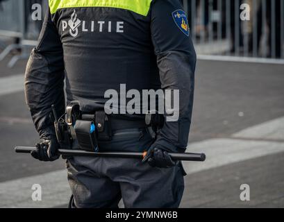 Rotterdam, pays-Bas, 21.11.2024, officier de police néerlandais tenant un bâton derrière son dos lors d'un rassemblement de protestation, vu de derrière Banque D'Images