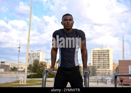 Jeune homme noir effectuant des exercices de calisthénie en plein air en milieu urbain Banque D'Images