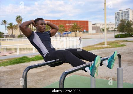 Jeune homme noir effectuant des sit-ups calisthéniques dans un parc urbain Banque D'Images