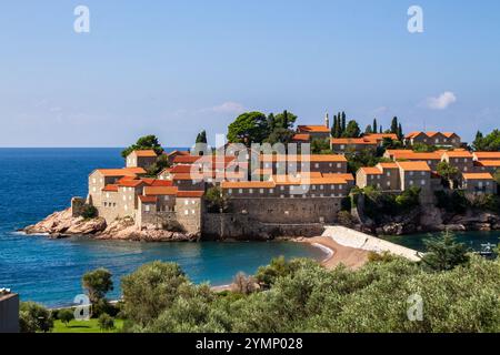 Un village côtier pittoresque avec des maisons en pierre surmontées de toits orange, entouré d'une végétation luxuriante, sur fond d'une mer bleu profond et c Banque D'Images