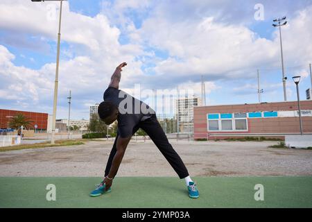 Jeune homme noir qui s'étire avant l'entraînement calisthénique à l'extérieur Banque D'Images