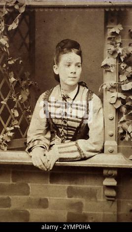 Portrait mis en scène photographie, carte de visite d'une jeune dame dans un cadre de fenêtre. Photographié à l'Ecole parisienne de photographie du 23 long Row, Market place, Nottingham, studio commercial appartenant à Walter Clayton entre 1874 et 1877. Banque D'Images