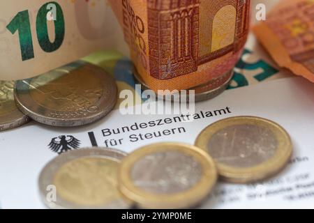 Berlin, Allemagne. 22 novembre 2024. Les pièces de monnaie et les billets de banque figurent sur une lettre du Bureau central fédéral des impôts. Le Bureau central fédéral des impôts (BZSt) fait partie du Ministère fédéral des Finances (BMF). Il s'agit d'une autorité fédérale supérieure qui relève du BMF et effectue diverses tâches dans le domaine de la fiscalité, telles que l'administration des numéros d'identification TVA, le traitement de l'échange automatisé d'informations et le traitement des remboursements d'impôts. Crédit : Fernando Gutierrez-Juarez/dpa/Alamy Live News Banque D'Images