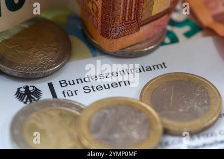 Berlin, Allemagne. 22 novembre 2024. Les pièces de monnaie et les billets de banque figurent sur une lettre du Bureau central fédéral des impôts. Le Bureau central fédéral des impôts (BZSt) fait partie du Ministère fédéral des Finances (BMF). Il s'agit d'une autorité fédérale supérieure qui relève du BMF et effectue diverses tâches dans le domaine de la fiscalité, telles que l'administration des numéros d'identification TVA, le traitement de l'échange automatisé d'informations et le traitement des remboursements d'impôts. Crédit : Fernando Gutierrez-Juarez/dpa/Alamy Live News Banque D'Images