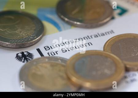 Berlin, Allemagne. 22 novembre 2024. Les pièces de monnaie et les billets de banque figurent sur une lettre du Bureau central fédéral des impôts. Le Bureau central fédéral des impôts (BZSt) fait partie du Ministère fédéral des Finances (BMF). Il s'agit d'une autorité fédérale supérieure qui relève du BMF et effectue diverses tâches dans le domaine de la fiscalité, telles que l'administration des numéros d'identification TVA, le traitement de l'échange automatisé d'informations et le traitement des remboursements d'impôts. Crédit : Fernando Gutierrez-Juarez/dpa/Alamy Live News Banque D'Images