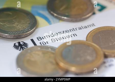 Berlin, Allemagne. 22 novembre 2024. Les pièces de monnaie et les billets de banque figurent sur une lettre du Bureau central fédéral des impôts. Le Bureau central fédéral des impôts (BZSt) fait partie du Ministère fédéral des Finances (BMF). Il s'agit d'une autorité fédérale supérieure qui relève du BMF et effectue diverses tâches dans le domaine de la fiscalité, telles que l'administration des numéros d'identification TVA, le traitement de l'échange automatisé d'informations et le traitement des remboursements d'impôts. Crédit : Fernando Gutierrez-Juarez/dpa/Alamy Live News Banque D'Images