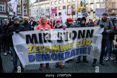 22 novembre 2024, Rhénanie-du-Nord-Westphalie, Aix-la-Chapelle : des manifestants se tiennent debout avec une pancarte indiquant « Mir Stonn (« nous sommes debout ») ensemble pour la démocratie » lors du rassemblement « nous sommes Aix-la-Chapelle » sur Theaterplatz. La manifestation est dirigée contre un événement de « dialogue avec les citoyens » organisé par l'AFD. Photo : Oliver Berg/dpa Banque D'Images