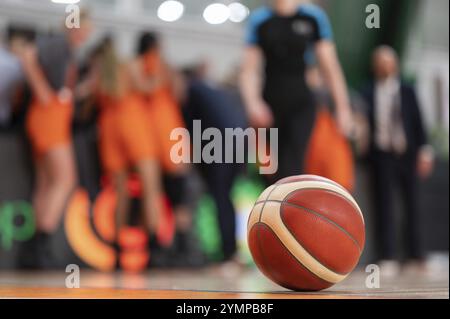 Le ballon couché sur le parquet et l'équipe de basket-ball en arrière-plan. Banque D'Images