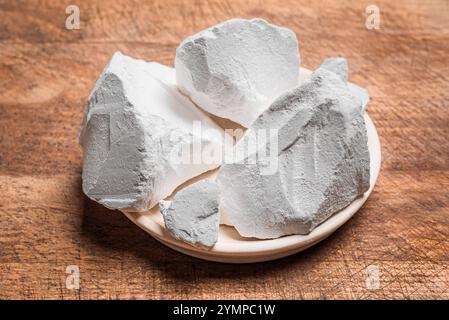 Morceaux d'argile blanche comestible ou de craie sur fond de bois gros plan. Argile calcique naturelle de roches de gypse pour manger. Banque D'Images