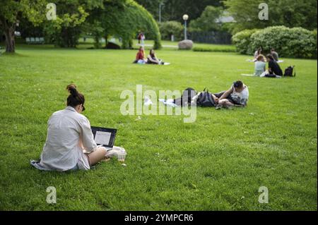 Les gens qui se reposent et travaillent sur la pelouse dans le parc Banque D'Images