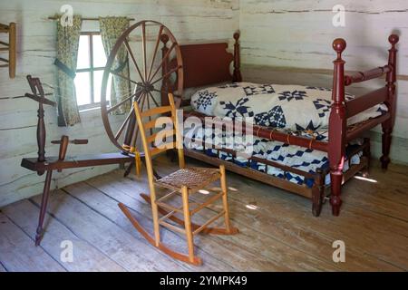 Petersburg, Illinois - Une roue qui tourne, un fauteuil à bascule et un lit gigogne dans une résidence du New Salem State Historic site de Lincoln. Le site est un R Banque D'Images