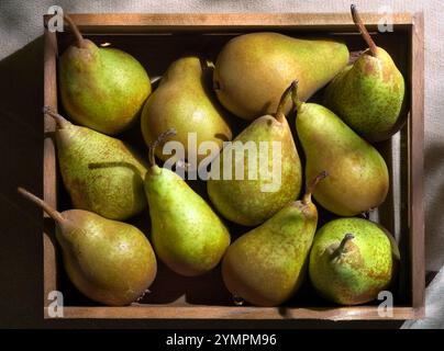 Poires vertes fraîches dans une caisse en bois, présentant des fruits biologiques mûrs idéaux pour une alimentation saine et des recettes. Banque D'Images