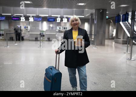 Femme adulte voyageant avec des bagages à main, sac à dos tient le passeport et attend le voyage de vol à l'aéroport international terminal. Femme d'âge moyen Go Banque D'Images