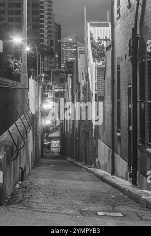 La banlieue de Sydney de The Rocks, établie lors de la colonisation en 1788, contient de nombreux sites classés au patrimoine et est la plus ancienne banlieue d'Australie. Ses bâtiments, escaliers et arcades ont été construits avec du grès local, d'où le nom de la région. Jusqu'aux années 1870, c'était un bidonville où les « gangs de rasoirs » flânaient la nuit dans les ruelles. C'est maintenant un quartier touristique chargé d'histoire entouré de Dawes point, Millers point et Barangaroo, souvent considéré comme faisant partie du quartier des Rocks. Sur la photo : une vue nocturne regardant vers le sud le long d'Argyle Lane à Millers point dans les Rocks, vu depuis Argyle place. Banque D'Images