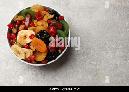 Mélange de différents fruits secs dans un bol sur une table texturée grise, vue de dessus. Espace pour le texte Banque D'Images