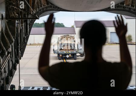 Brianna Ralston, aviateur senior de l'US Air Force, capitaine de chargement du 16e escadron de transport aérien, guide un chargeur k transportant des marchandises sur un avion cargo C-17 Globemaster III pendant la semaine tactique de masse du bataillon à l'aérodrome de Pope Army, Caroline du Nord, le 19 novembre 2024. BMTW est un exercice de grande envergure, de plusieurs jours, qui améliore la préparation, l'interopérabilité et les capacités de mission tout en affinant les compétences nécessaires pour exécuter des opérations aéroportées complexes, cruciales pour assurer la préparation à l'intervention mondiale. (Photo de l'US Air Force par Christian Silvera, aviateur principal) Banque D'Images