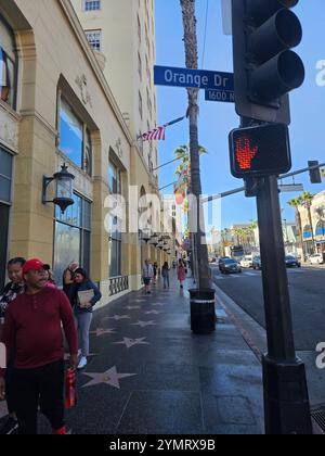 'Hollywood Walk of Fame sur une journée ensoleillée, avec des touristes, des palmiers, et le panneau de rue emblématique Orange Drive. Parfait pour les thèmes du tourisme et cit Banque D'Images