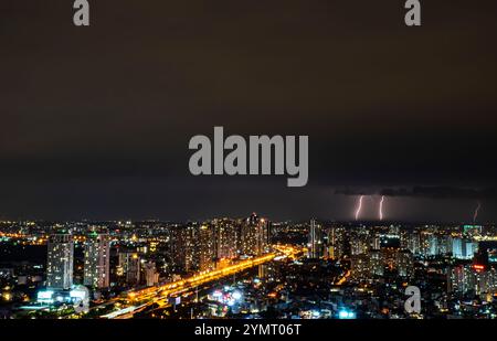 Une ville la nuit avec une tempête dans le ciel. Le ciel est sombre et nuageux. Il y a beaucoup de bâtiments dans la ville Banque D'Images