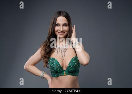 Danseuse du ventre jouant avec costume vert vif dans un cadre de studio Banque D'Images