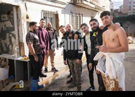 Torrente, Espagne - 22 novembre 2024. Résidents gitans du quartier de Xenillet, la zone la plus touchée de Torrente lors des inondations de la DANA. Ils vivent à côté du lit de la rivière et l'une d'elles, une femme, a perdu sa maison, la première juste au bord du ravin. Son fils regarde le paysage désolé. Il s’agit d’un groupe de jeunes hommes lors des opérations de nettoyage, aidés par Salvati per servire, une association évangélique accréditée par la Protezione civile italienne. Maisons détruites. Crédit : Roberto Arosio/Alamy Live News Banque D'Images